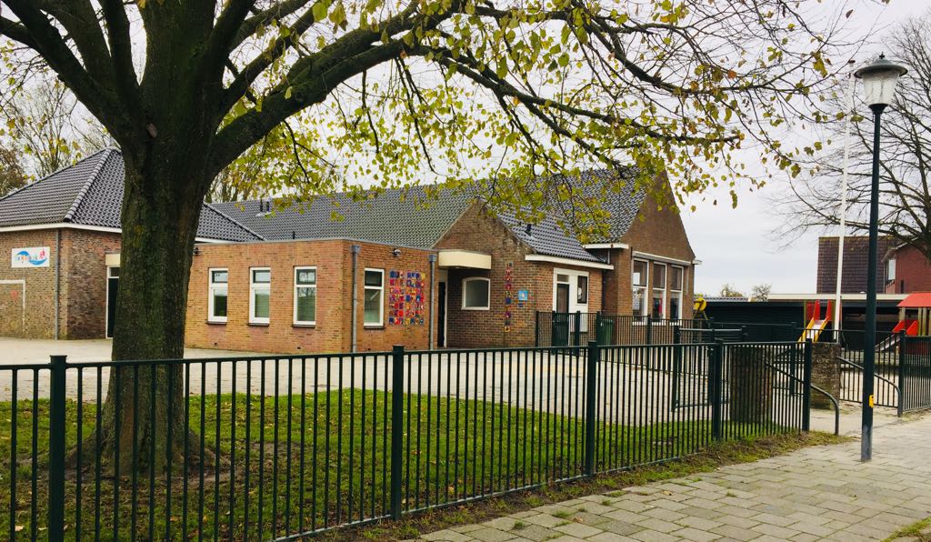 Ons gebouw in Kommerzijl, met de grote boom en het hek rond het plein